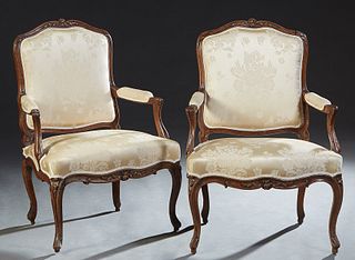 Pair of French Louis XV Style Carved Cherry Fauteuils, late 19th c., the canted arched floral carved upholstered back over upholstered arms and an uph