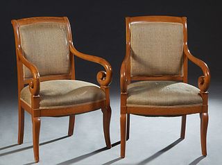 Pair of French Empire Style Carved Walnut Fauteuils, 20th c., the canted curved upholstered back flanked by round scrolled arms, over a bowed seat, in