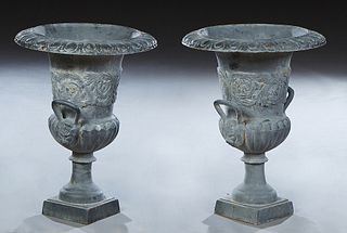Pair of Cast Iron Relief Planters, 20th/21st c., the campana form urn with floral relief sides and two lion's head ring handles, on an integral square