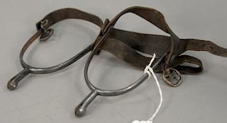 Two pairs of iron spurs with leather straps.