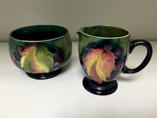 A Moorcroft leaves and berries pattern milk jug and sugar basin, decorated to a green ground painted
