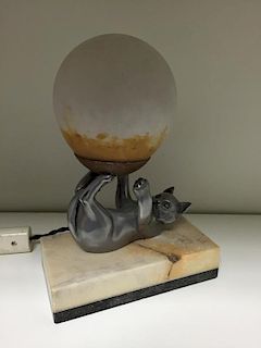 An Art Deco desk lamp, in the form of a spelter cat upon its back supporting a glass shade with its