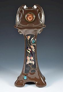 A Bretby Pottery Art Nouveau mantle clock, the front panel decorated with an orientalist finch on a