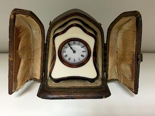 An early 20th century ivory and tortoiseshell miniature carriage clock, the shaped case raised on to