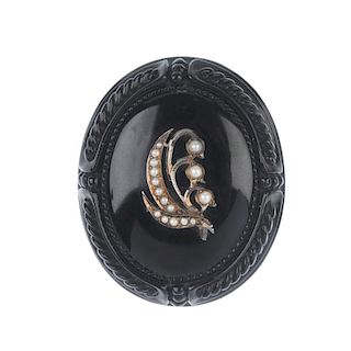 A late Victorian memorial jet and split pearl brooch. Of oval outline, the outer edge with carved ro