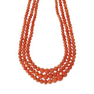 A three-row coral bead necklace. Comprising three rows of graduated spherical coral beads measuring
