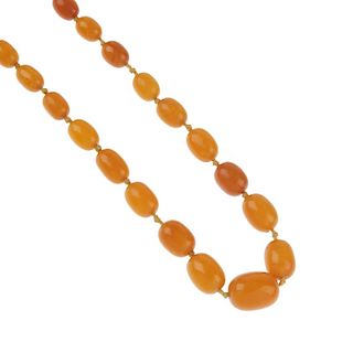 A natural amber bead necklace. Comprising twenty-seven graduating oval-shape natural amber beads, me