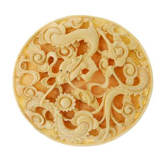 An early 20th century carved ivory panel. The oval-shape panel carved as a dragon amongst stylised c