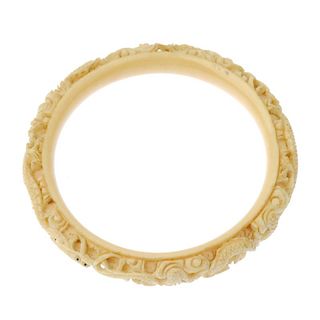 An early 20th century carved ivory bangle and pair of ear pendants. To include a circular bangle car