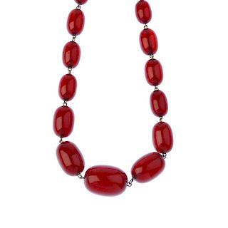 A red plastic bead necklace. Comprising thirty-two graduated oval-shape plastic beads, measuring 2.2