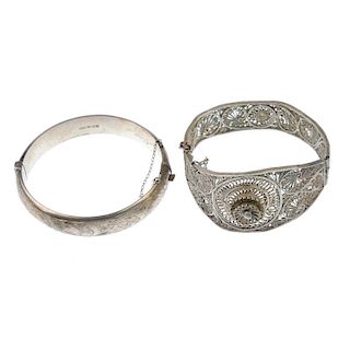 A selection of bangles. To include a hinged filigree bangle with flower detail and an Egyptianesque