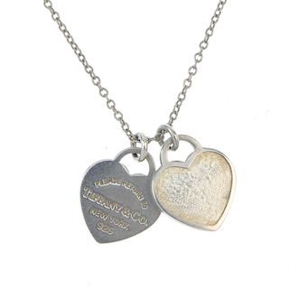 TIFFANY & CO. - a pendant. Designed as a chain, suspending two small heart charms, one reading 'Plea