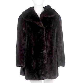 A three-quarter length dark ranch mink coat. Designed with a lapel collar, hook and eye fastenings,