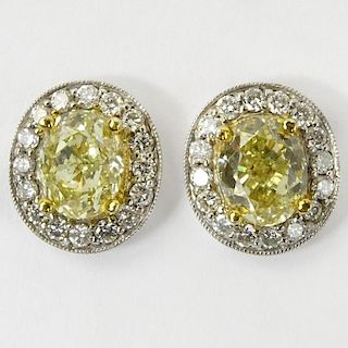 Pair of Approx. 2.05 Carat Oval Cut Fancy Yellow Diamond, .50 Carat Round Cut Diamond, 14 Karat White Gold and 18 Karat Yellow Gold Earrings.