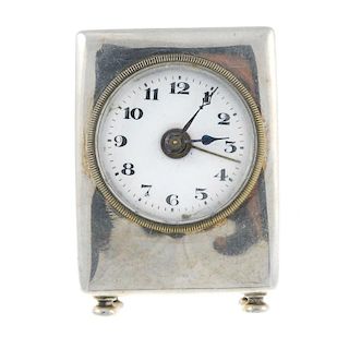 An alarm travel clock. White metal case. Manual wind movement with alarm complication. White enamel