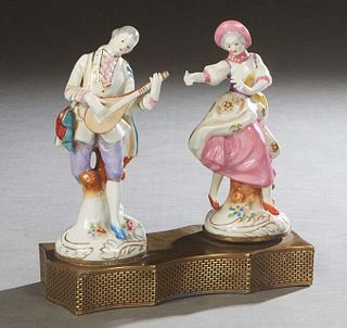 Pair of German Musical Porcelain Figurines, c. 1900, of a male musician and a female dancer, on a serpentine pierced brass base. She rotates to wind t