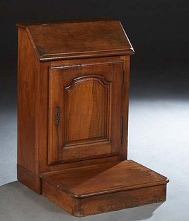French Provincial Louis XIV Style Carved Walnut Prie Dieu, early 20th c., the slant lid top opening to storage, over a fielded panel cupboard door wit