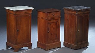 Group of Three French Louis Philippe Style Carved Walnut Nightstands, early 20th c., one with a gray marble top over a frieze drawer and a long cupboa