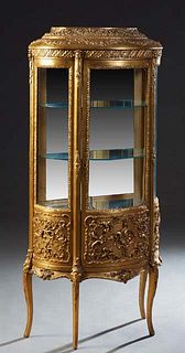 Louis XVI Style Gilt and Gesso Curved Glass Vitrine, early 20th c., the relief decorated stepped oval top over a center door with a curved glass upper