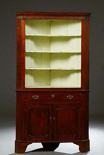 English Carved Mahogany Corner Cabinet, 19th c., with a dentillated crown over a fretwork frieze above three open shaped shelves above a frieze drawer