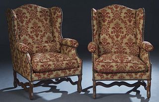 Pair of French Louis XIII Style Carved Oak Wing Chairs, early 20th c., the arched upholstered canted wing back over rolled cushioned arms flanking a r
