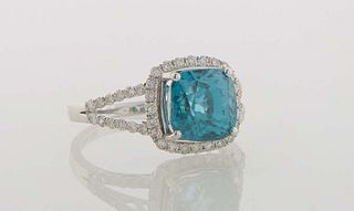Lady's 14K White Gold Dinner Ring, with a cushion cut 5.87 carat blue zircon atop a border of small round diamonds, the split sides of the band also m