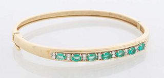 14K Yellow Gold Emerald and Diamond Hinged Bangle Bracelet, mounted with seven oval emeralds flanked by eight bands of two .03 cts. diamonds, total di