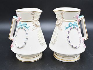 Pair of Belleek Painted Florence Jugs, having wreath and bows, mask form spout, having black mark, height 7 1/2 inches. Provenance: Collections of Nor