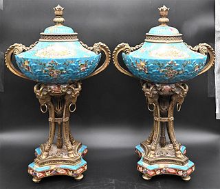 Pair of Porcelain Urns, having bronze mounts, rams head, and hoof support, on platform base, height 21 inches.