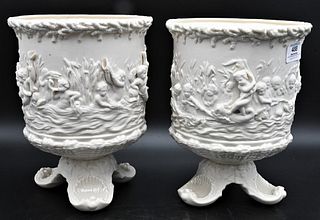 Pair of Belleek Naiads Jardinieres, each having mould putti sides on footed base, remnants of early black mark, height 10 inches, diameter 8 inches. P