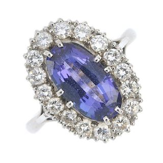An 18ct gold tanzanite and diamond cluster ring. The oval-shape tanzanite, within a brilliant-cut di