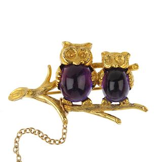 A 9ct gold amethyst owl brooch. Designed as two owls, with oval amethyst cabochon bodies, perched at
