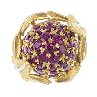 A 1950s 18ct gold ruby dress ring. The pave-set ruby bombe panel, within a bi-colour, textured folia
