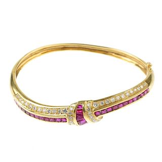 A ruby and diamond hinged bangle. The front designed as a series of calibre-cut ruby and pave-set di