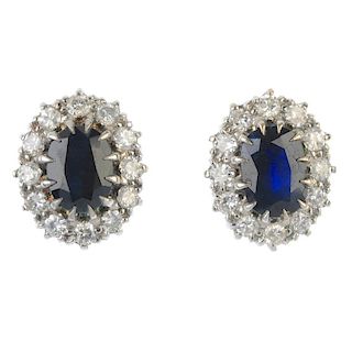 A pair of 18ct gold sapphire and diamond earrings. Each designed as an oval-shape sapphire, within a