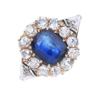 A sapphire and diamond cluster ring. The cushion-shape sapphire, within an old-cut diamond surround,