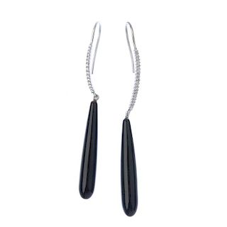 A pair of onyx and diamond ear pendants. Each designed as a tapered onyx drop, suspended from a bril