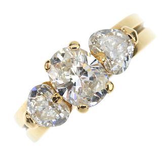 An 18ct gold diamond three-stone ring. The oval-shape diamond, with heart-shape diamond sides, to th