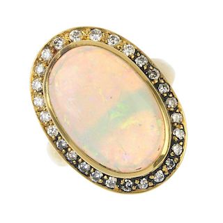 An opal and diamond cluster ring. The oval opal cabochon, within a brilliant-cut diamond surround, t