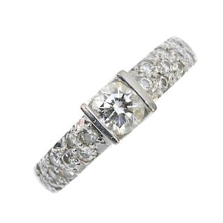 A diamond single-stone ring. The brilliant-cut diamond, to the pave-set diamond shoulders and plain