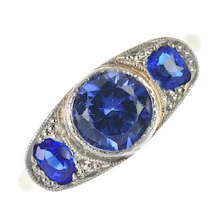 A synthetic sapphire and garnet-top-doublet three-stone ring. The circular-shape synthetic sapphire,