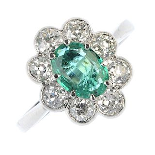 Emerald and diamond floral cluster ring. The oval-shape emerald, within an old-cut diamond scalloped