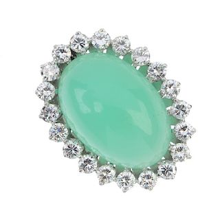 A jade and diamond cluster ring. The oval jade cabochon, within a brilliant-cut diamond surround, to