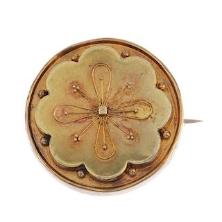 A late Victorian gold floral brooch, circa 1880. The cannetille flower, within an undulating border,
