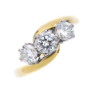 An 18ct gold diamond three-stone crossover ring. The slightly graduated brilliant-cut diamonds, to t