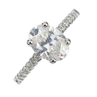 A platinum diamond single-stone ring. The oval-shape diamond, to the brilliant-cut diamond line shou