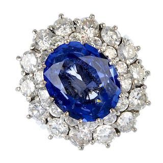 A sapphire and diamond cluster ring. The oval-shape sapphire, within a graduated brilliant-cut diamo