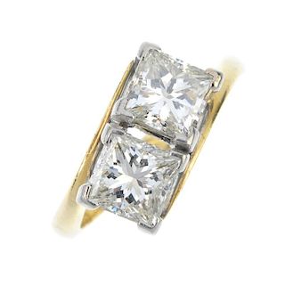 An 18ct gold diamond two-stone crossover ring. The square-shape diamond duo, to the asymmetric shoul