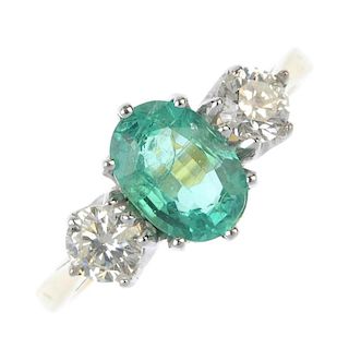 An emerald and diamond three-stone ring. The oval-shape emerald, to the brilliant-cut diamond should