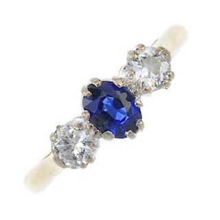 An 18ct gold sapphire and diamond three-stone ring. The oval-shape sapphire, to the brilliant-curt d